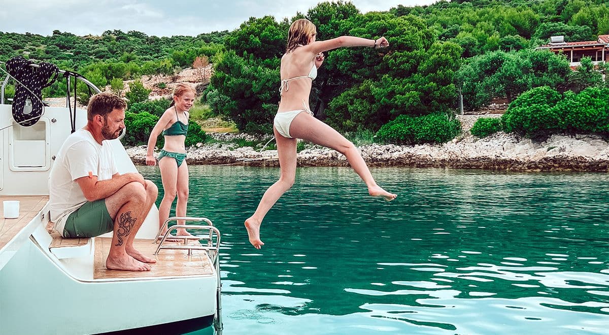 Barn hoppar från en båt i Kroatien